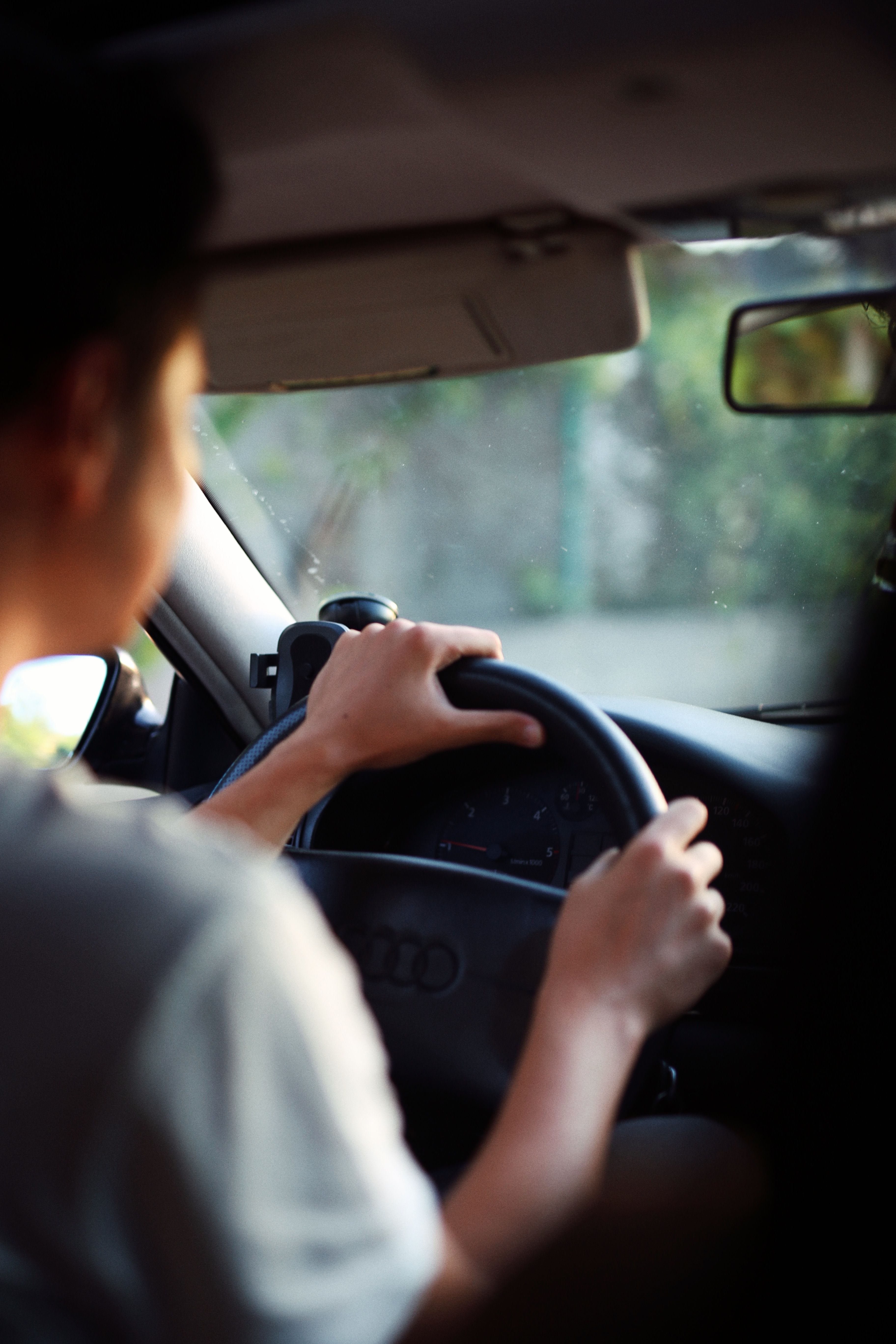 Close-up of a person driving an Audi car showcasing hands on the steering wheel and dashboard view.